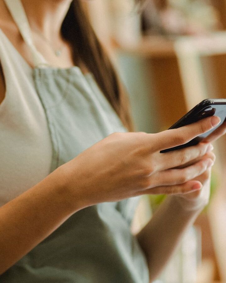 A shop owner checking customer messages on her phone at the counter